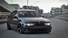 Черный бумер BMW 5 series на узкой улочке